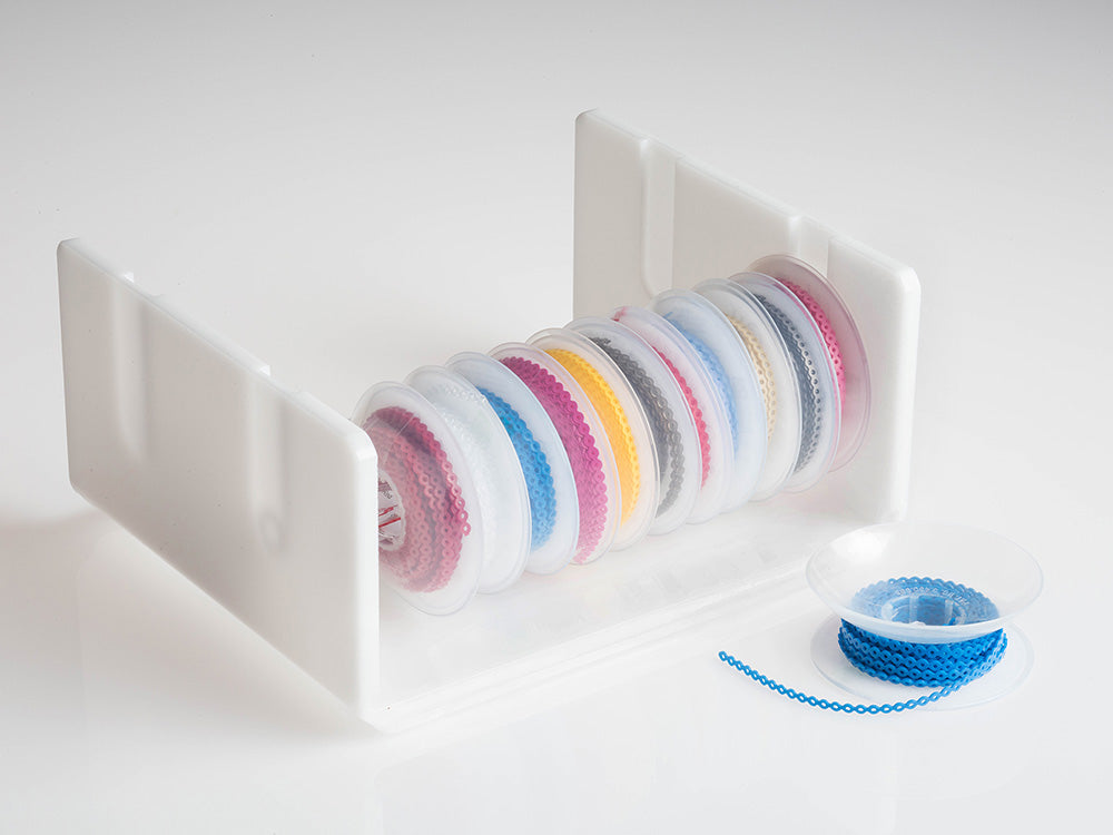 G&H Dyna-Link elastomeric chain spools in assorted colours on a dispenser rack